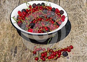 Fresh colorful berries in bowl on rustic wooden table