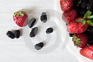 Colorful strawberries and mulberries in white bowl