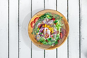 Fresh colorful vegetable salad on a white wooden table