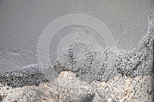 Fresh concrete mixture spreads over an old rough ground surface during active construction work