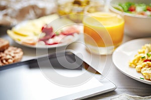 Fresh continental breakfast. Tablet, black screen, selective focus.