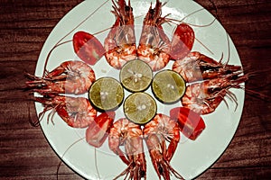 Fresh cooked shrimps with limes, tomatos on white plate. Red prawns. Healthy delicious seafood dinner lunch. Diet concept. Sea