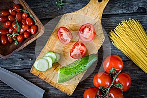 Fresh cooking ingredients on wooden cutting board. Tomatoes and cucumbers