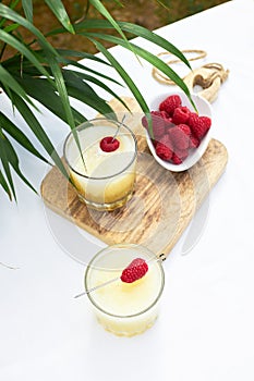 Fresh cool cocktail of melon with ice and lime slices, garnished with fresh raspberries. Summer drinks and smoothies