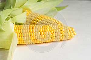 Fresh corn on the cob on a wooden white table, close-up