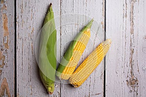 Fresh corn cobs on flat wooden background