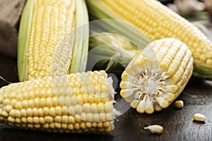 Fresh corn on cobs on rustic wooden table, closeup