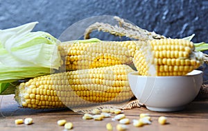 Fresh corn on cobs and sweet corn ears on rustic wooden table background