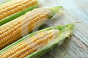 Fresh corn cobs on wooden background, closeup