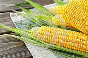 Fresh corn cobs on wooden background, closeup