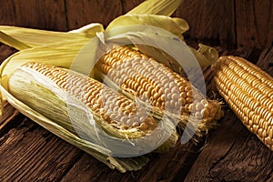 Fresh corn on cobs on wooden table