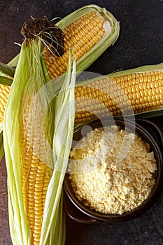 Fresh Corn and corn grits in bowl on black table