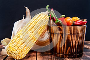 Fresh corncob with peppers and tomatoes organic vegetables natural food in wooden bucket, mexican