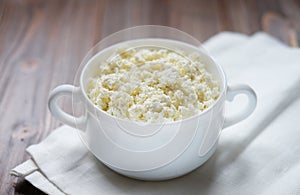 Fresh cottage cheese in a bowl on a wooden table.