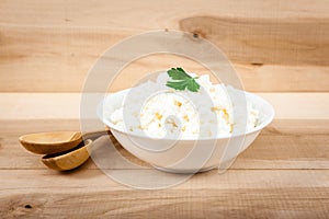 Fresh cottage cheese in a white bowl on a wooden table