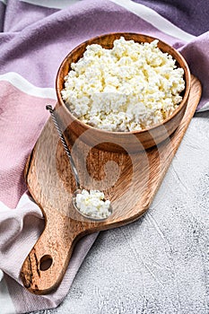 Fresh Cottage cheese in a wooden bowl. Gray background. Top view