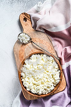 Fresh Cottage cheese in a wooden bowl. Gray background. Top view