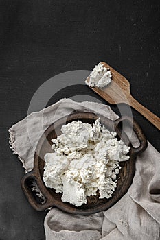 Fresh cottage cheese on a wooden plate top view
