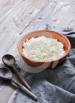 Fresh cottage cheese with wooden spoons on a rustic wooden background.