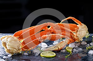 Fresh crab claws, lime, spices, spices, ice, shrimp, vegetables on a dark background. Delicious seafood, healthy food