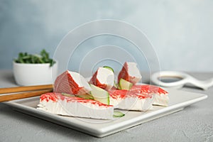 Fresh crab sticks with cucumber served on grey table, closeup