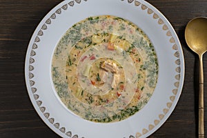 Fresh creamy salmon fish soup with potatoes, carrots, broccoli, peppers and onions in a ceramic plate on a wooden table. A