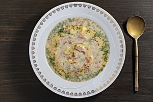 Fresh creamy salmon fish soup with potatoes, carrots, broccoli, peppers and onions in a ceramic plate on a wooden table. A