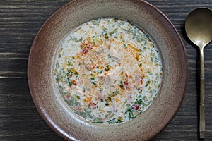 Fresh creamy salmon fish soup with potatoes, carrots, peppers and onions in a ceramic plate on a wooden table, close-up. A