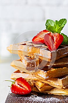 Fresh crisp Belgian waffles with ripe strawberries, mint and honey for breakfast