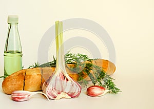 Fresh crispy baguette with garlic oil and herbs. A delicious still life of baguette, young garlic, fresh dill and a glass bottle