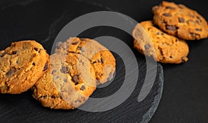 Fresh crispy chocolate chip cookies on a dark table