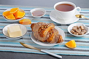 Fresh croissant with butter and tea, orange for breakfast