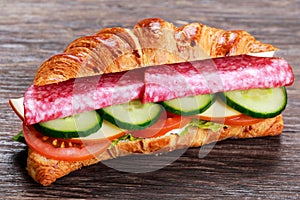 Fresh croissant with salami, chesse and vegetables