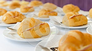 Fresh croissant sandwich with ham and cheese on white plate. tea time and coffee break at conference meeting business