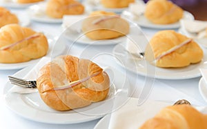 Fresh croissant sandwich with ham and cheese on white plate. tea time and coffee break at conference meeting business