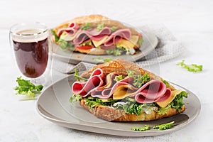 Fresh croissant or sandwich with salad, ham and cheese on light  background