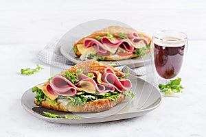 Fresh croissant or sandwich with salad, ham and cheese on light  background