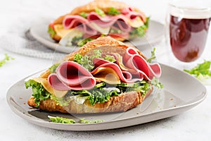 Fresh croissant or sandwich with salad, ham and cheese on light  background
