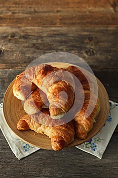 Fresh croissant in a wooden plate on table