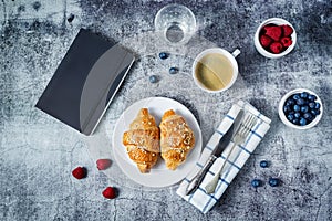Fresh croissants with berries and cup of coffee