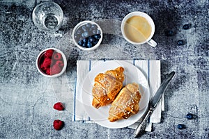 Fresh croissants with berries and cup of coffee