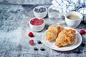 Fresh croissants with berries and cup of coffee