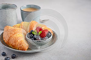 Fresh Croissants with berries on a gray concrete background
