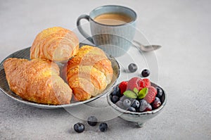 Fresh Croissants with berries on a gray concrete background