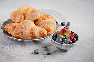 Fresh Croissants with berries on a gray concrete background.