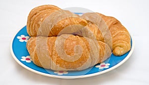 Fresh croissants on blue daisy decorative plate