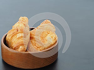 Fresh croissants bread in wood bowl on black table in background with area copy spcae for some text photo