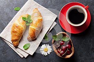 Fresh croissants, cherry berries and coffee cup