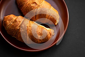 Fresh croissants on a clay plate on a dark background