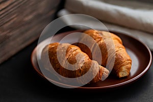 Fresh croissants on a clay plate on a dark background